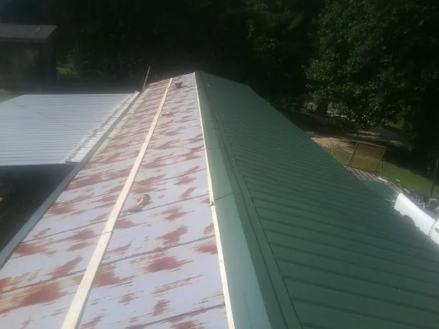 Old rusted panels beside newly installed green metal roofing — Wind Damage Roof Repair by Roofing Brothers in Hinesville