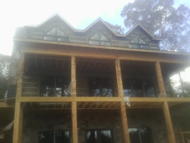 Dormers and porch framing on a large log home under construction — Roof Coating work by our crew in Hinesville
