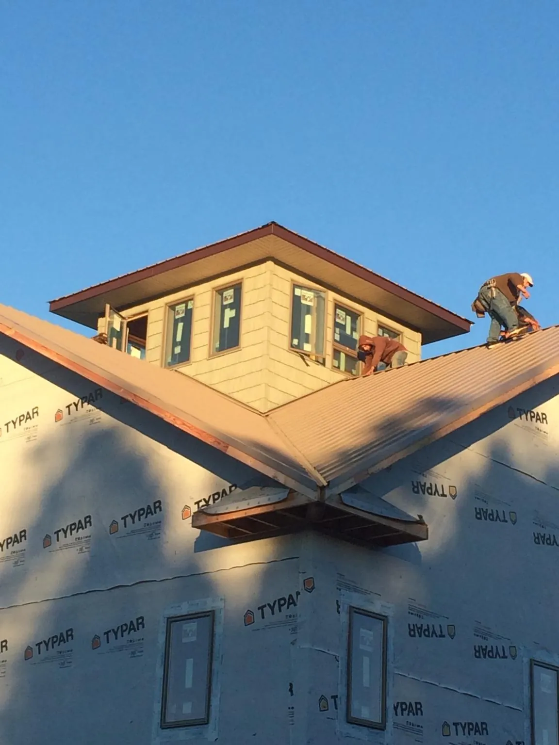 Roofers working around a rooftop cupola on a new metal roof at sunset — Roof Waterproofing in Hinesville by Roofing Brothers